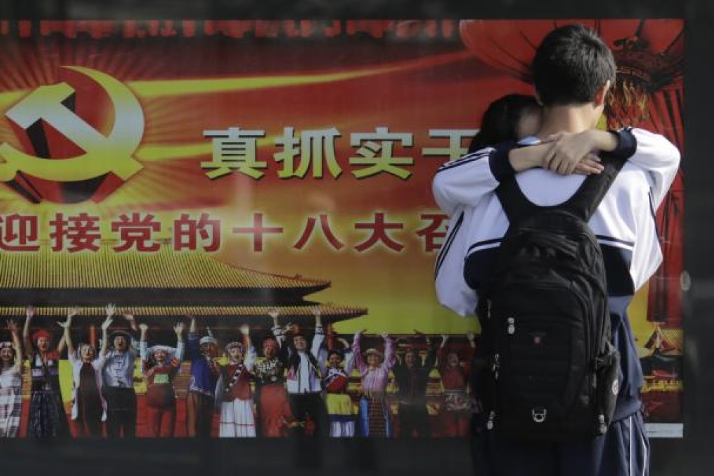 A young couple share a romantic moment in front of an official 18th Party Congress propaganda poster in Shanghai. Photo: AP