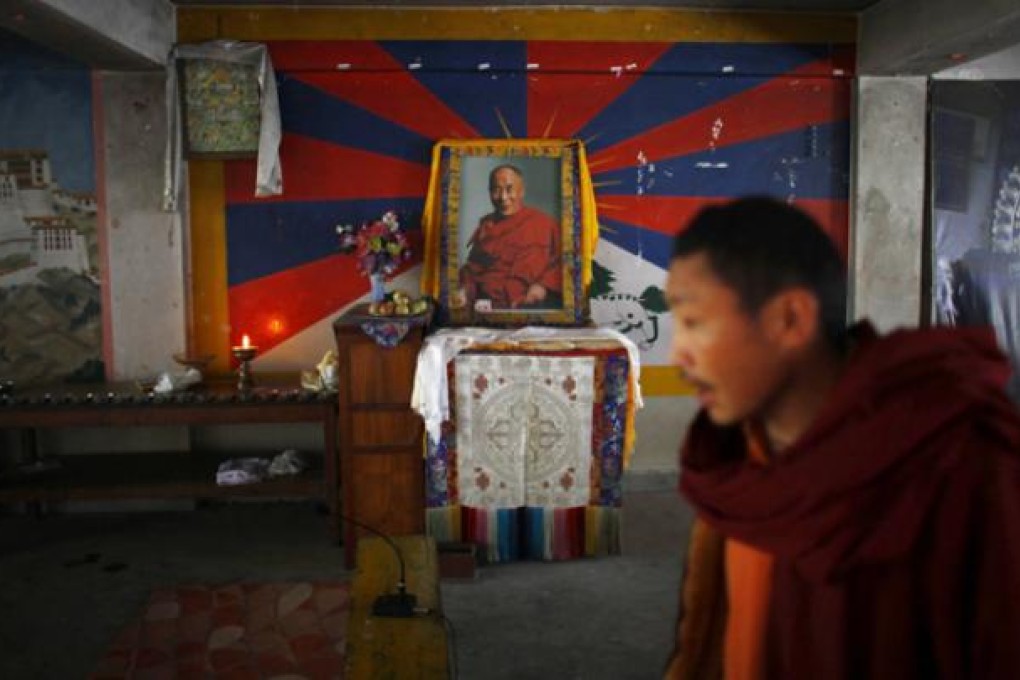 An exiled Tibetan monk walks past a portrait of spiritual leader the Dalai Lama during a prayer ceremony to display solidarity towards Tibetans who have self-immolated, protesting China's rule, in Katmandu on Saturday. Photo: AP