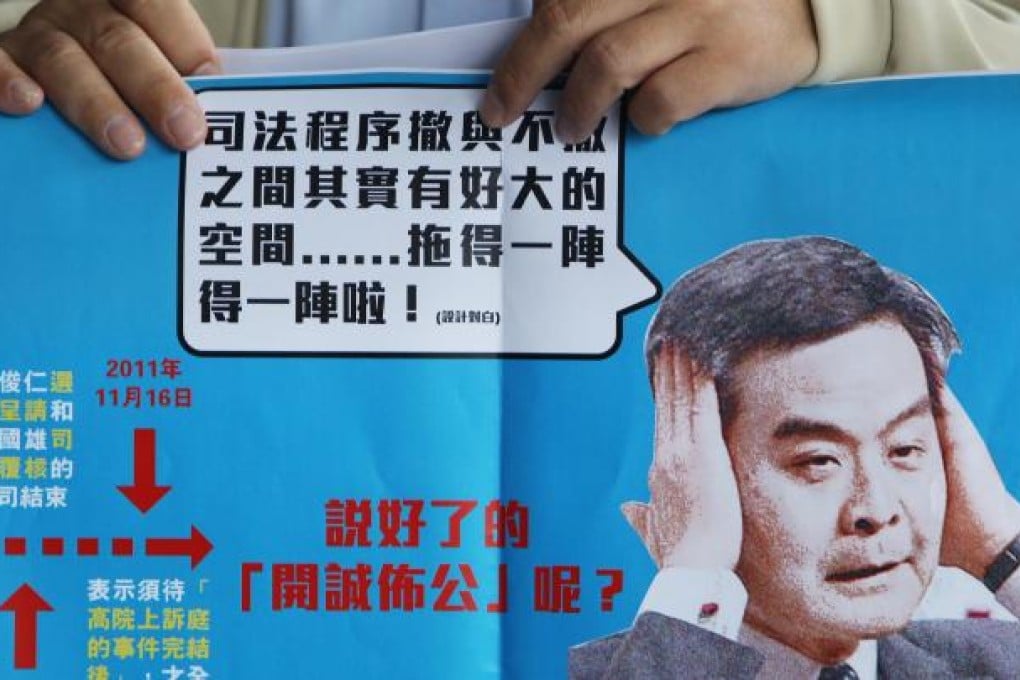 A member of the Association for Democracy and People's Livelihood holds a placard urging Leung Chun-ying to explain the illegal structures at his homes on the Peak. Photo: Sam Tsang