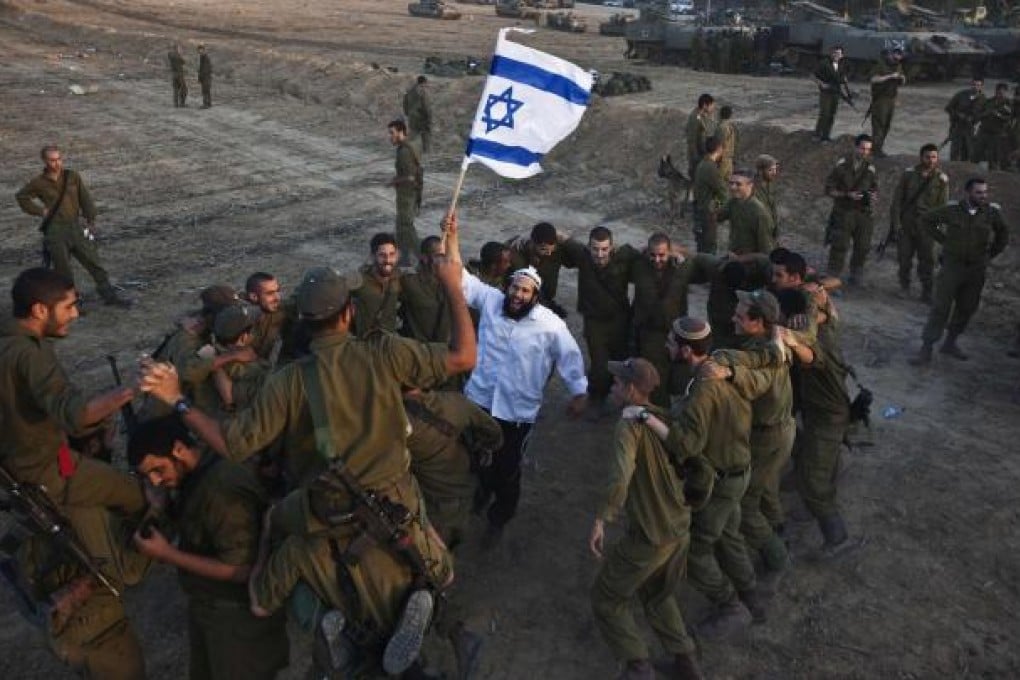 A Hasidic Jewish man dances with Israeli troops during a visit to support the soldiers near the border with the Gaza Strip. Photo: Reuters