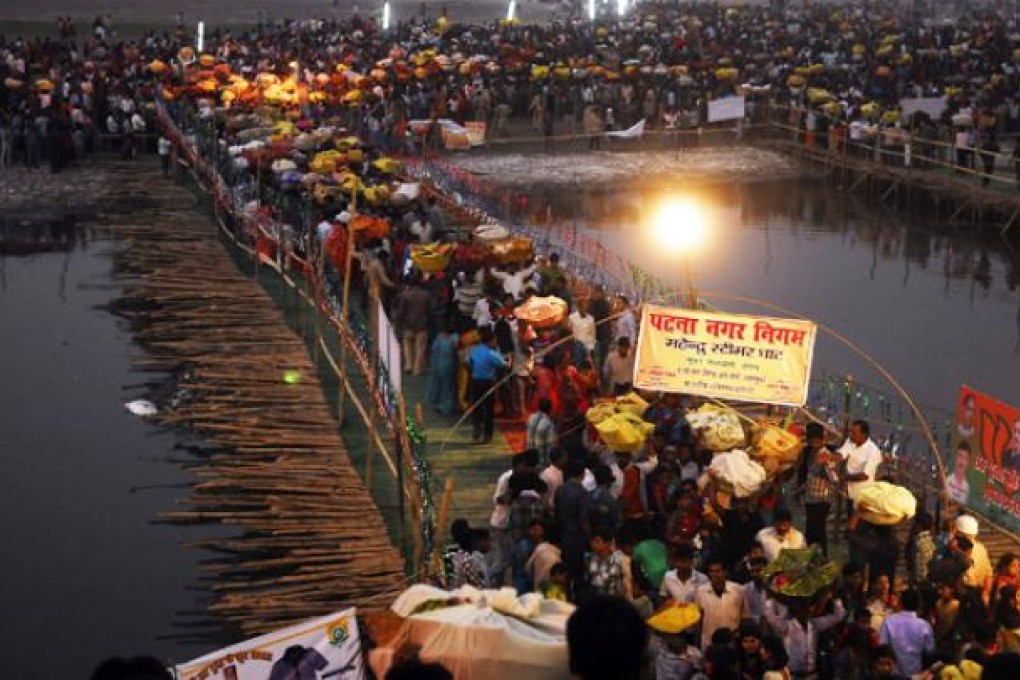 Indian Hindu devotees cross a bamboo bridge as they gather to pay homage to the setting sun on the banks of the Ganges River on Monday. Photo: AFP