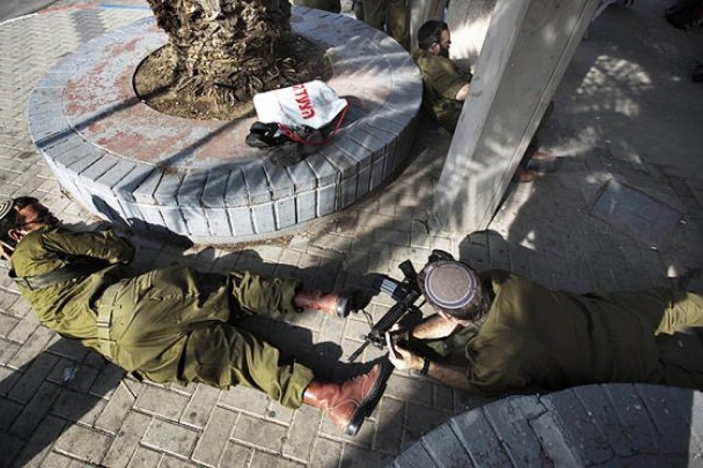 Israeli soldiers take cover during a rocket attack from the Gaza Strip in Yad Mordechay, southern Israel. Photo: AFP