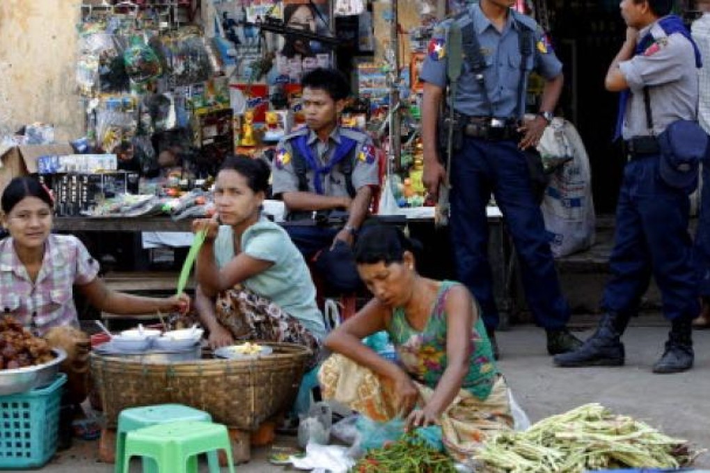 Myanmar policemen stand guard as Rakhine people sell snacks and vegetables at the Sittwe market, Sittwe, western Myanmar. Photo: AP