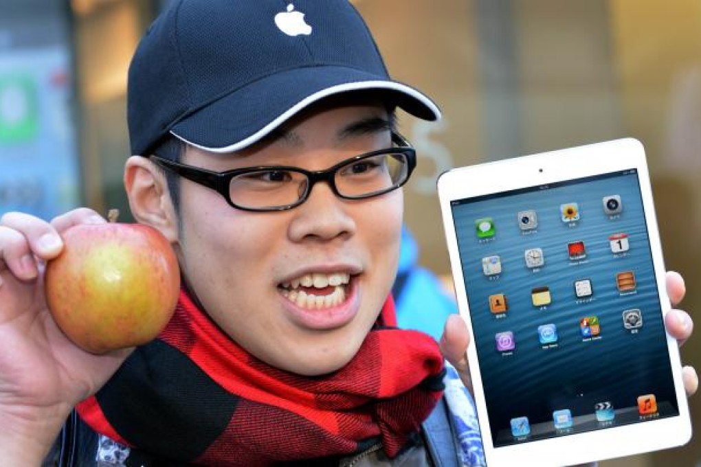 A customer holds up an apple as he purchases Apple's new 7-inch sized "iPad mini" tablet at an Apple store in Tokyo on November 2, 2012. Photo: AFP