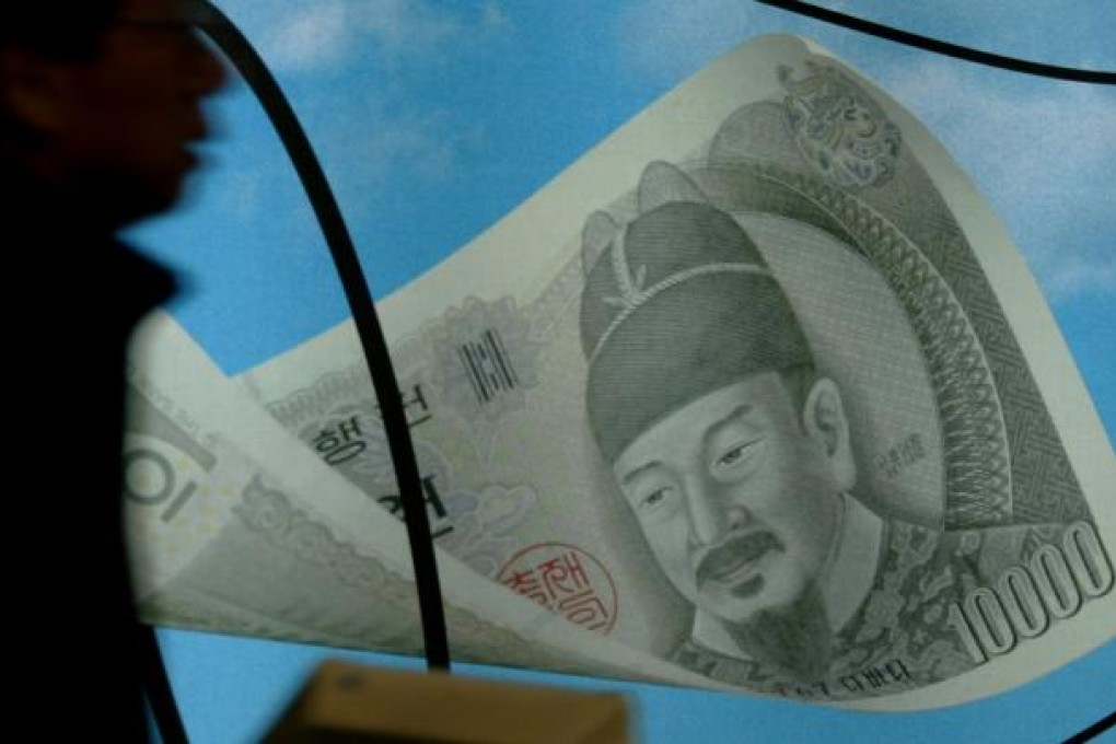A South Korean walks past a signboard featuring the South Korean won in Seoul. Photo: Reuters