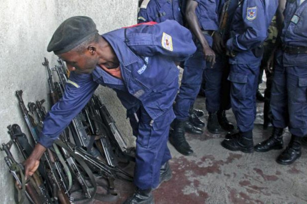 A Congo government policeman hands in his weapon to M23 rebels in Goma, Congo. Photo: AP