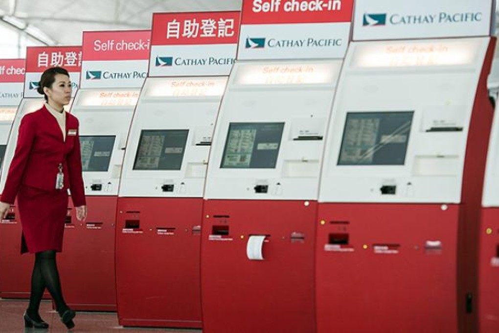 A Cathay Pacific employee walks past self check-in booths at Chek Lap Kok airport. Photo: AFP