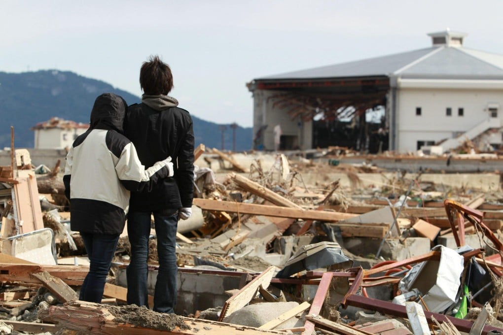 A man and his sister stand before their broken house, destroyed by the tsunami at Rikuzentakata in Iwate prefecture. Photo: AFP