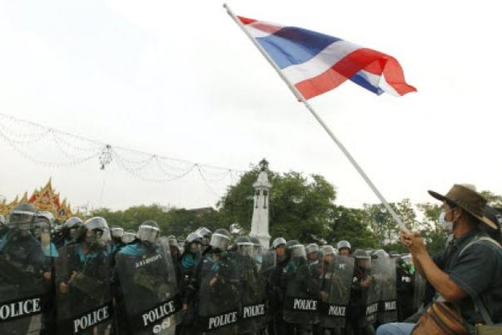 A anti-government Pitak Siam wave Thai national flag in front of Thai riot polices at Makkawan bridge near the Government House in Bangkok on Thailand. Photo: EPA