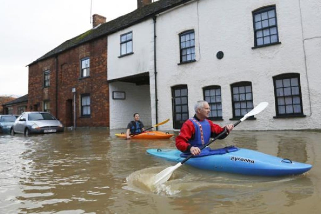 People use canoes to travel through floodwaters in Malmesbury in Wiltshire, western England, on Sunday. Photo: AFP