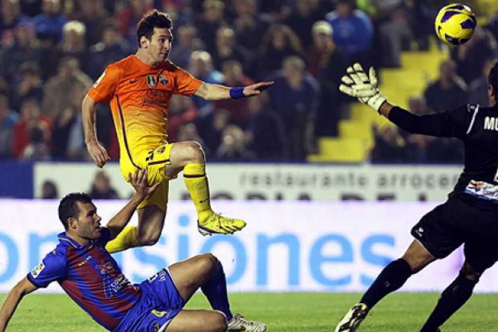 Lionel Messi (centre) scores against Levante's goalkeeper Gustavo Munua (right) and defender David Navarro on Sunday. Photo: EPA