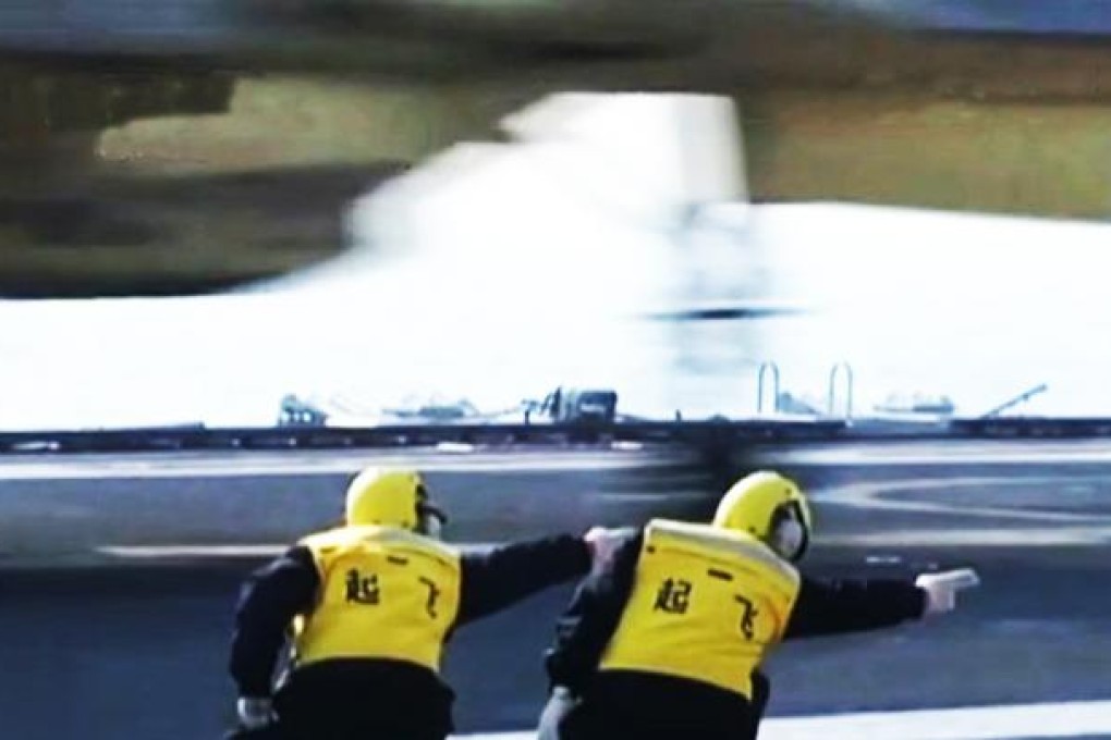 Two crew members direct J-15 fighter jets for take-off on the deck of China's first aircraft carrier, the Liaoning.