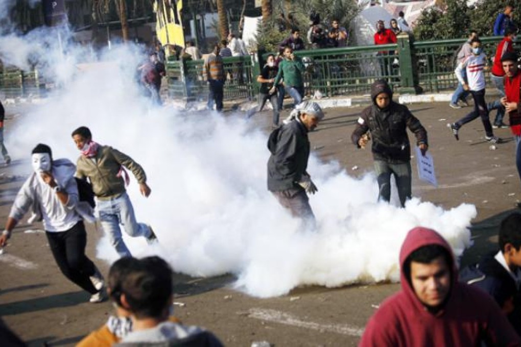 Demonstrators run away from tear gas during clashes with riot police on Omar Makram street, off Tarir Square, on Wednesday. Photo: AFP