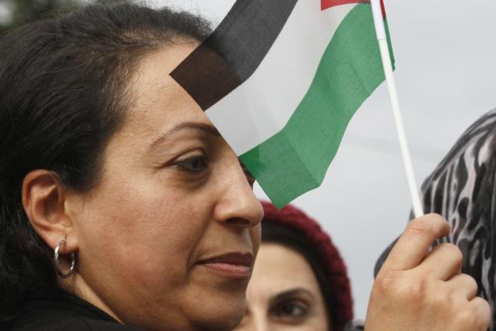 A Palestinian woman hold up a small Palestinian flag as she takes part in a rally in support of the efforts of Palestinian President Mahmud Abbas to secure a diplomatic upgrade. Photo: AFP