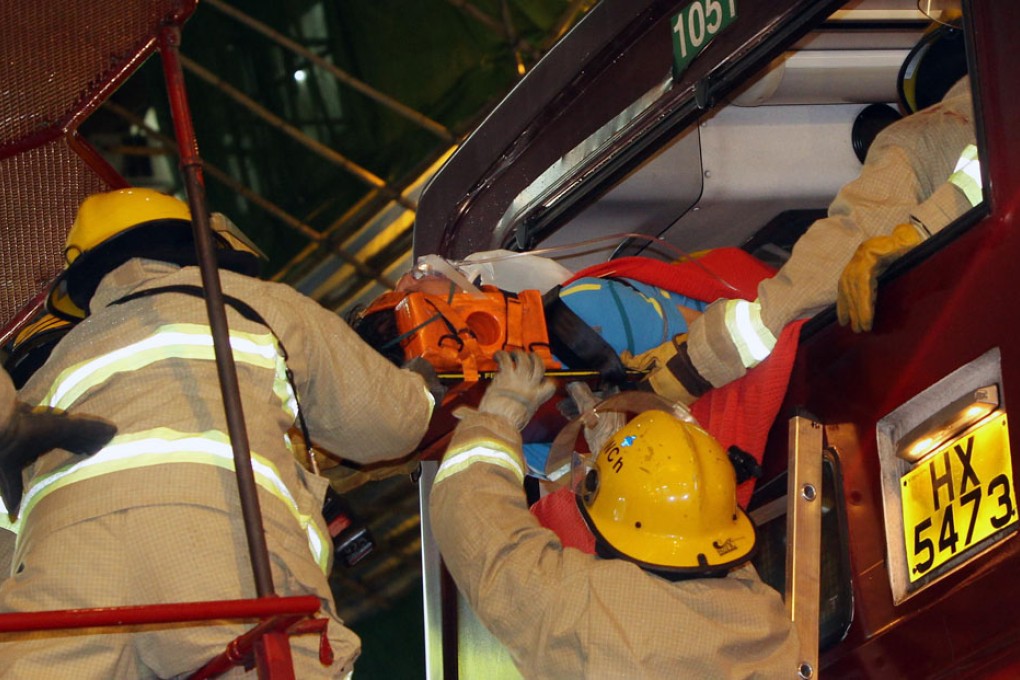 One of 55 injured in a three-way collision at a Wan Chai bus stop yesterday is removed from the wreckage by rescuers. One passenger was seriously hurt, with two others trapped for 20 minutes. Photo: David Wong