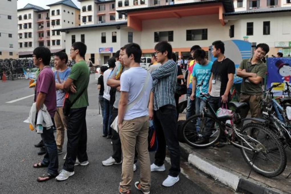 Foreign workers wait for their transportation to work outside their dormitory in Singapore on Monday. Photo: AFP