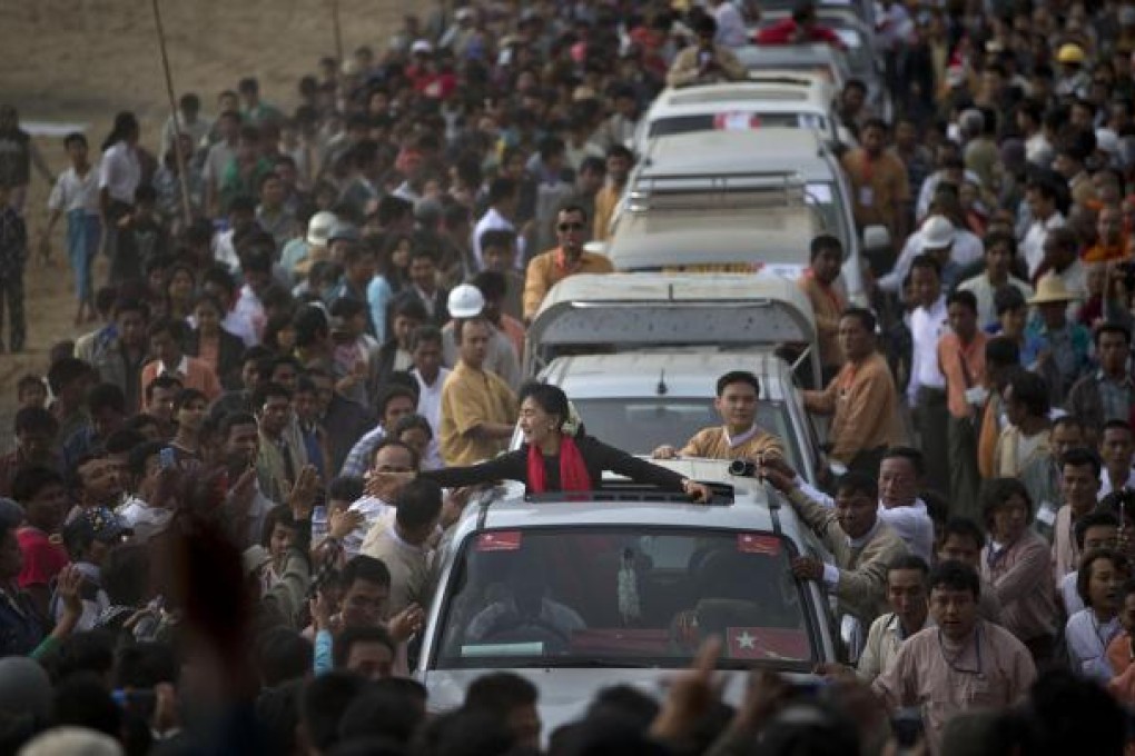 Opposition leader Aung San Suu Kyi reaches out to supporters as she leaves after a public meeting close to Letpadaung mine. She has taken a soft line on the conflict, suggesting Myanmar honour the mining contract. Photo: AP