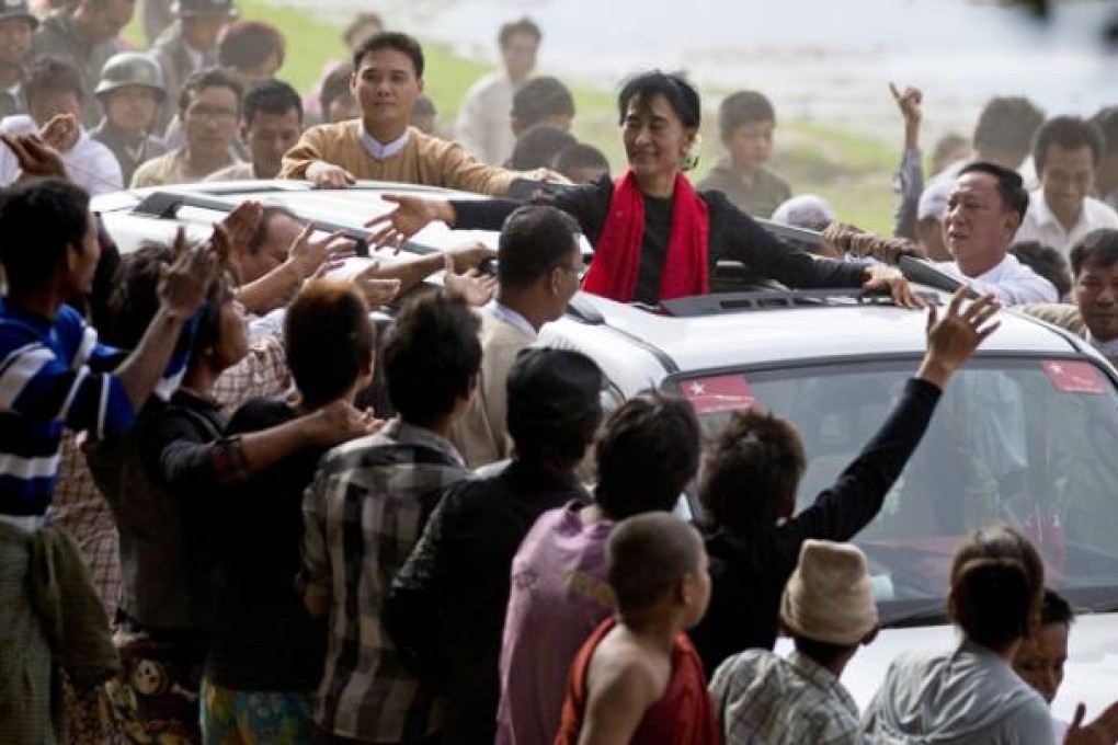 Supporters of opposition leader Aung San Suu Kyi reach to touch her hand as she leaves after a public meeting close to Letpadaung mine in Monywa on Friday. Photo: AP