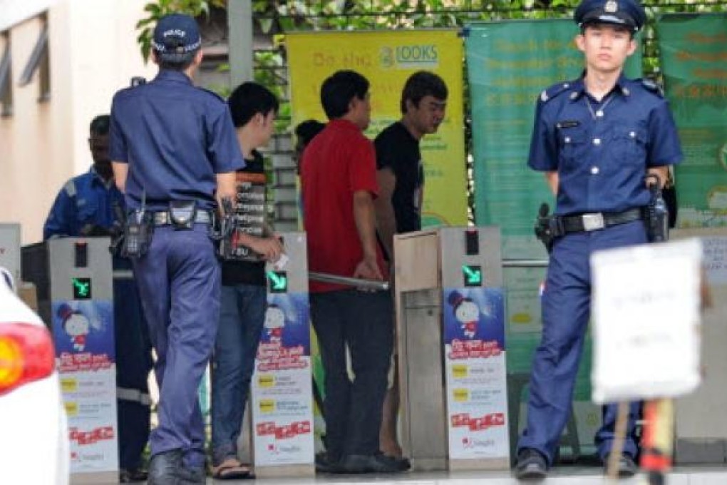 Policemen stand by the entrance to a foreign workers dormitory in Singapore. More than 100 mainland bus drivers in Singapore refused to work in a rare case of labour mass action. Photo: AFP