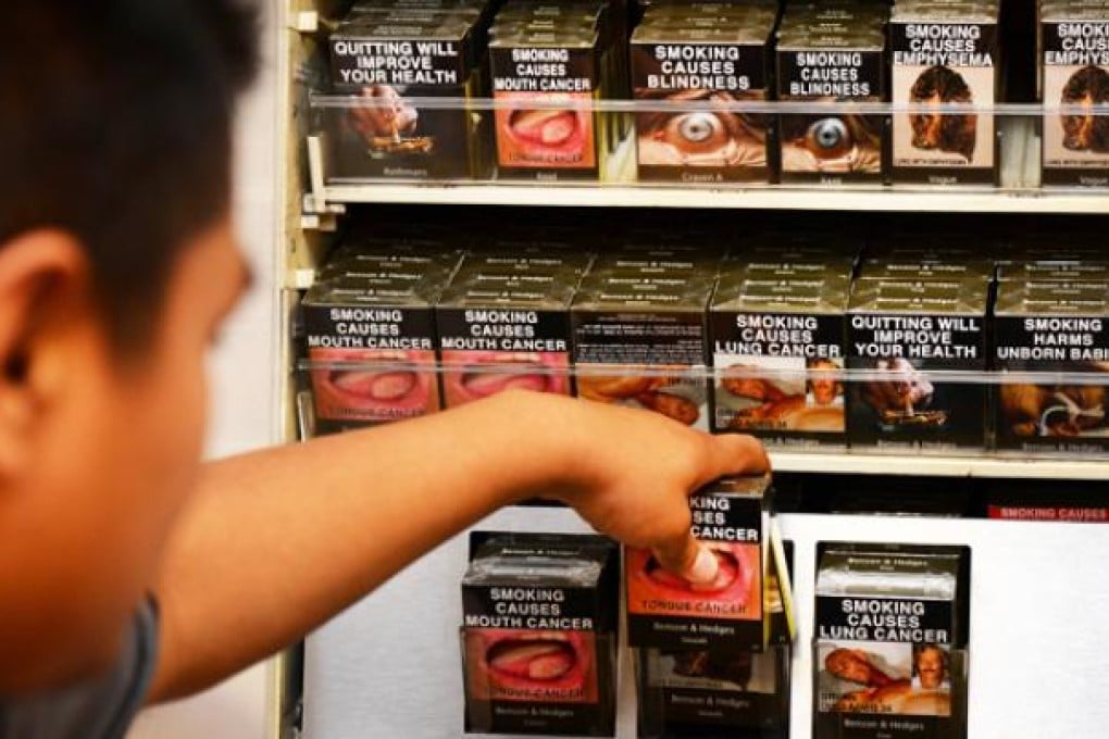 An employee in a bookshop adjusts identically packaged cigarettes in Sydney on Saturday. Photo: AFP