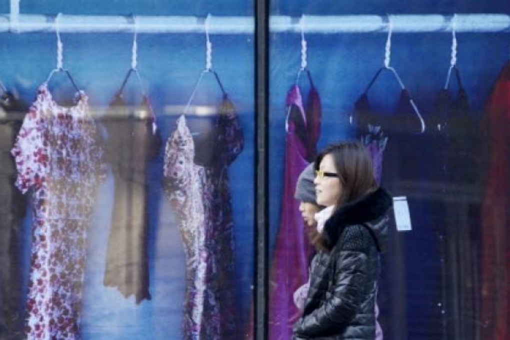 Two Chinese women make their way past a clothing shop in Beijing on November 29, 2012. Photo: AFP