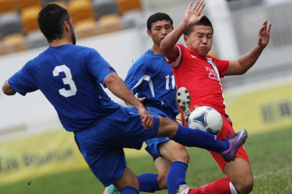 Hong Kong's Luk Chi-ho takes on Guam's Scott Guerrero and Dylan Naputi in their EAFF East Asian Cup match yesterday. Photo: Nora Tong