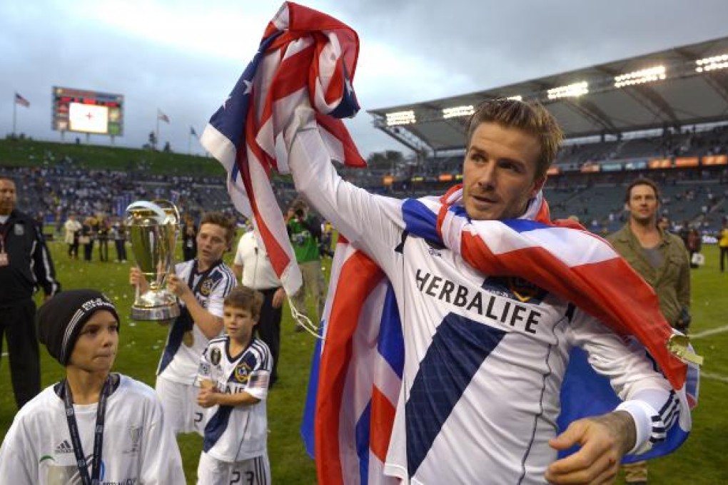 LA Galaxy's David Beckham, right, waves to fans as his sons from left, Romeo, Brooklyn and Cruz follow after winning the MLS Cup championship match 3-1 against the Houston Dynamo on Saturday. Photo: AP