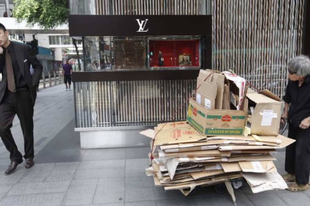 An elderly woman in Central pushes a trolley loaded with cardboard boxes for recycling, a means of earning some extra cash. Photo: EPA