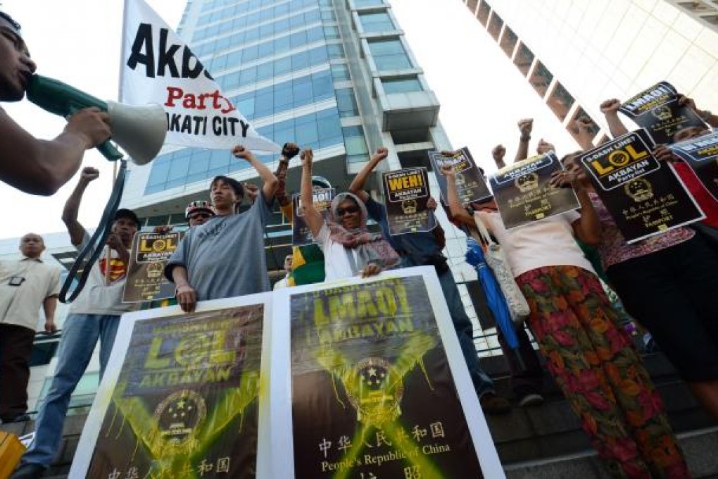 Protesters holding mock covers of Chinese passports raise clinched fists as they shout anti-Chinese slogans during a demonstration in front of the Chinese consular office. Photo: AFP
