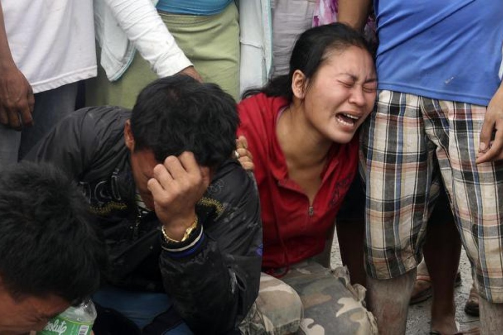 Relatives weep as they view bodies recovered from floods in New Bataan in the Compostela Valley. Scores remain missing. Photo: AP