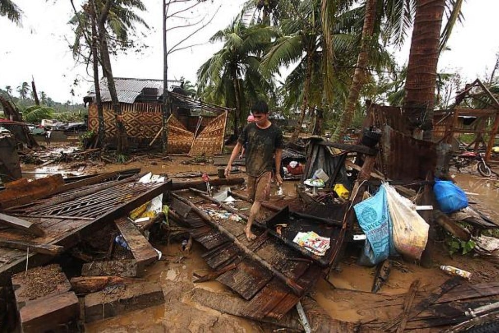 Residents walk among wrecked houses after the storm hit Compostela town in Mindanao. Photo: AFP