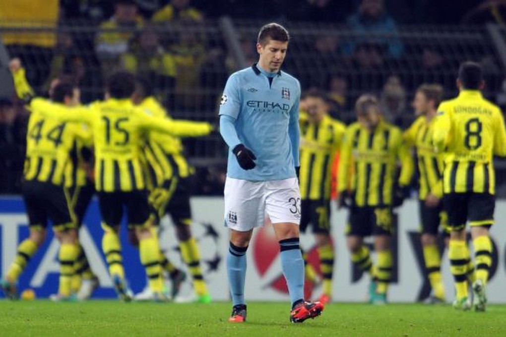 Manchester City's Matija Nastasic walks away dejected as Borussia Dortmund players celebrate victory in their Champions League group D match in Dortmund. Photo: EPA