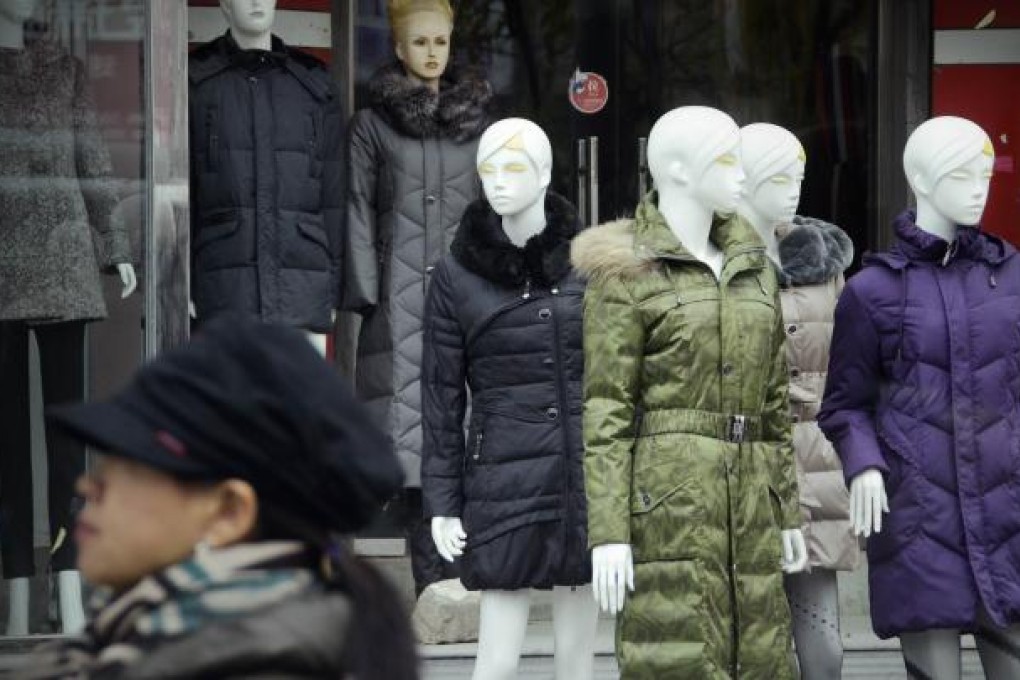 A woman passes a Beijing clothing shop. The latest purchasing managers index from HSBC Holdings and Markit Economics said China’s services industries expanded more slowly in November. Photo: AFP