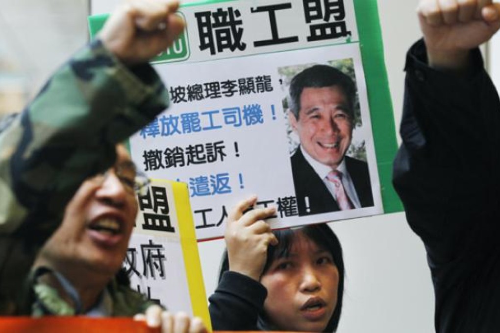 Members of a labour union hold placards with pictures of Singapore's Prime Minister Lee Hsien Loong reading 'Release the striking bus driver, restrict a charge' near the Singapore Consulate General in Hong Kong on Wednesday. Photo: AP
