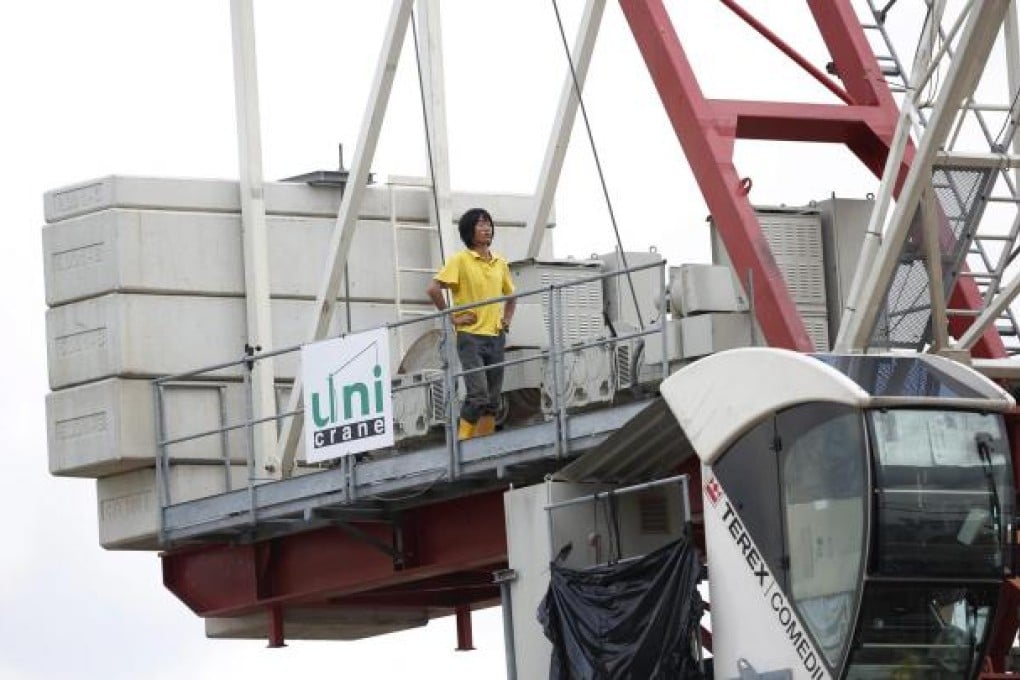 One of the two Chinese construction workers continues his protest on top of a crane. Photo: EPA