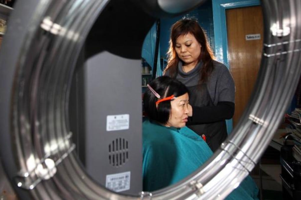 Nepalese beauty shop owner Lama Mima Sambu gives community worker Caroline Simick a quick trim. Photo: Felix Wong