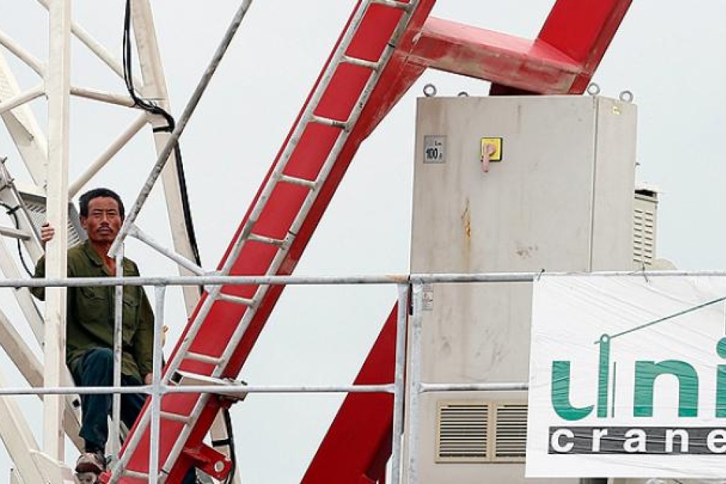 One of two Chinese construction workers protesting working conditions stands on top of a crane at a building site in Singapore on Thursday. Photo: EPA