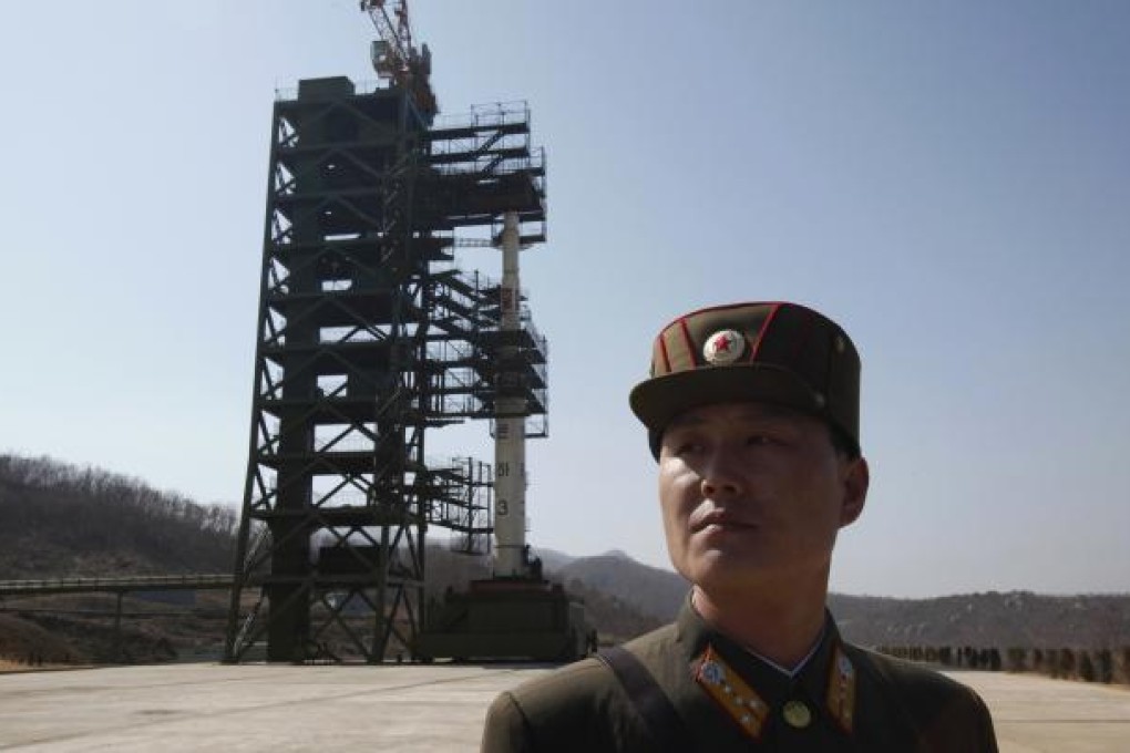 A soldier stands guard in front of a rocket sitting on a launch pad at the West Sea Satellite Launch Site. Photo: Reuters