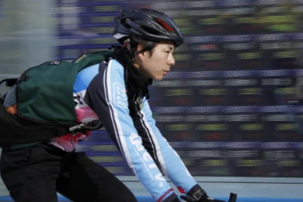 A deliveryman cycles past an electronic stock board of a securities firm in Tokyo, Thursday, Dec. 6, 2012. Photo: AP