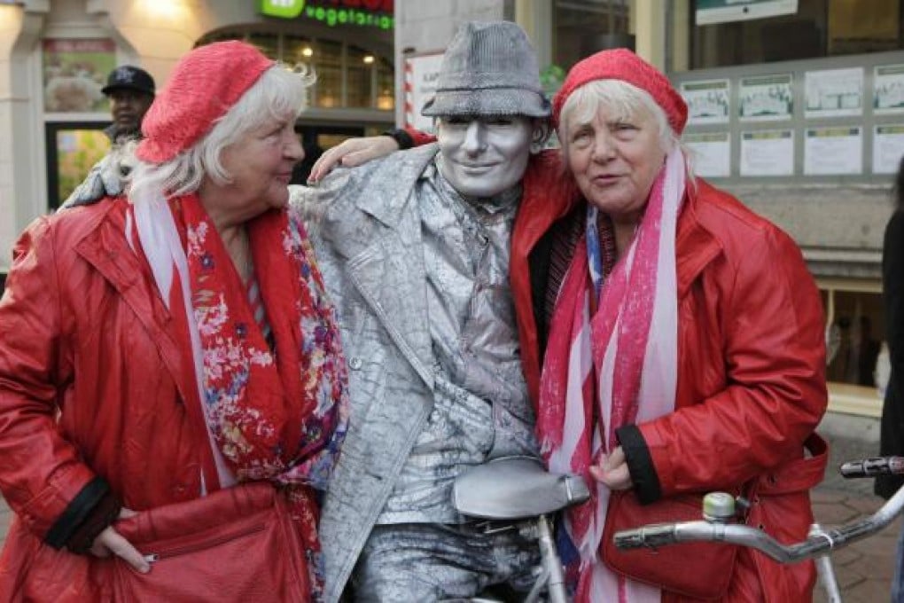 Louise and Martine Fokkens pose with a street artist. Photo: AFP