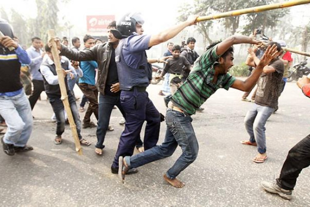 An opposition activist tries to escape as the police and pro-government activists beat him during countrywide road block protests in Bangladesh on Sunday. Photo: EPA