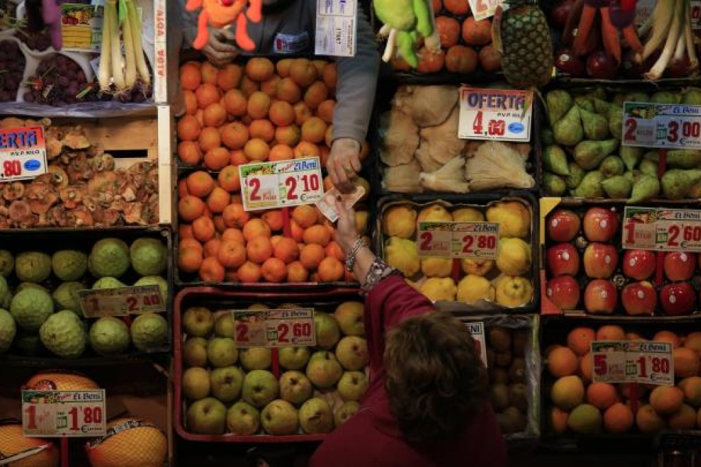 A woman buys from a greengrocer's assistant at a market in Spain, which has been hard hit by the euro-zone crisis. Photo: Reuters
