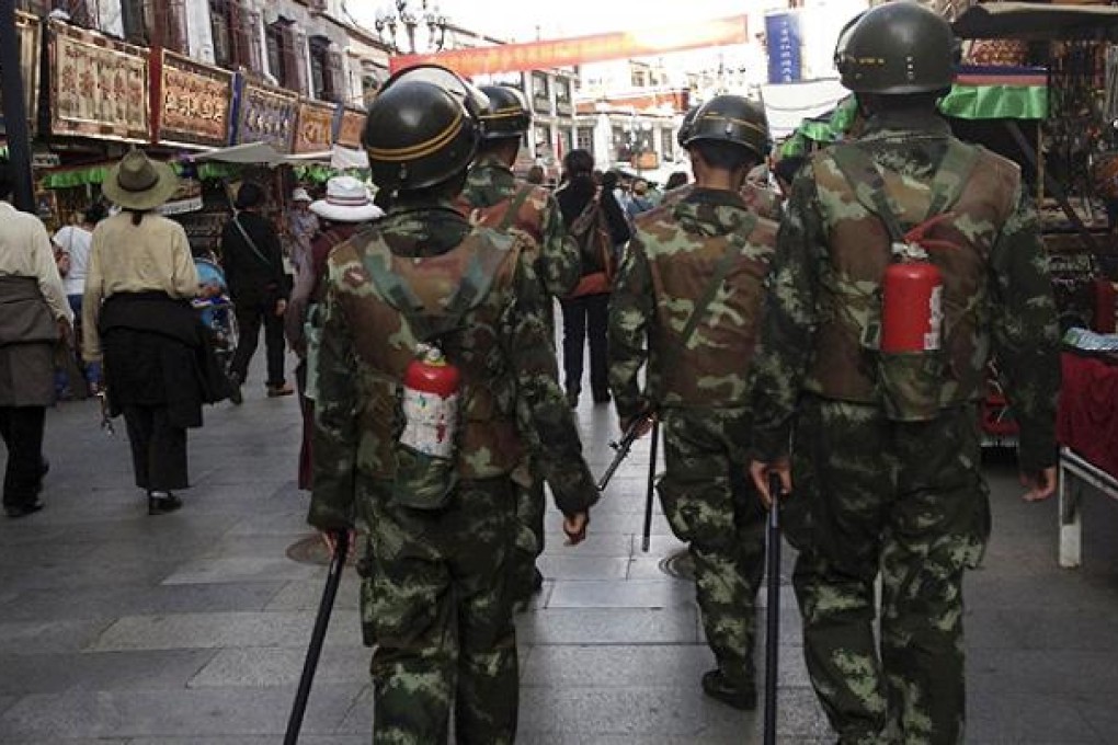 Paramilitary policemen patrol the streets of Lhasa equipped with fire extinguishers. Photo: Reuters