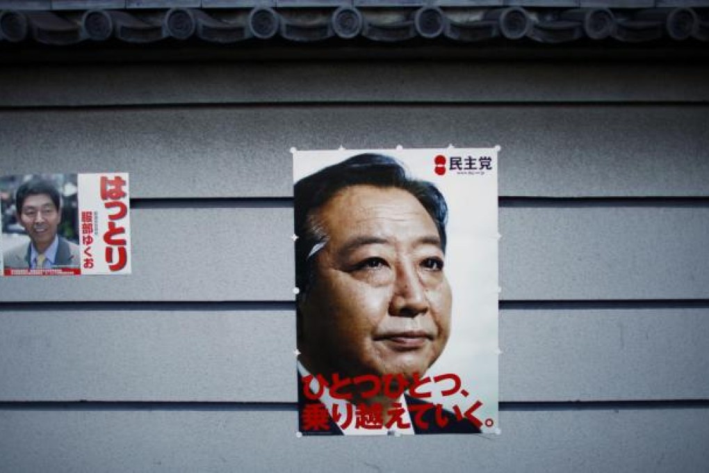 An election poster of Prime Minister Yoshihiko Noda (right) is pasted on a Tokyo wall, next to that of a parliamentary candidate. Photo: AP