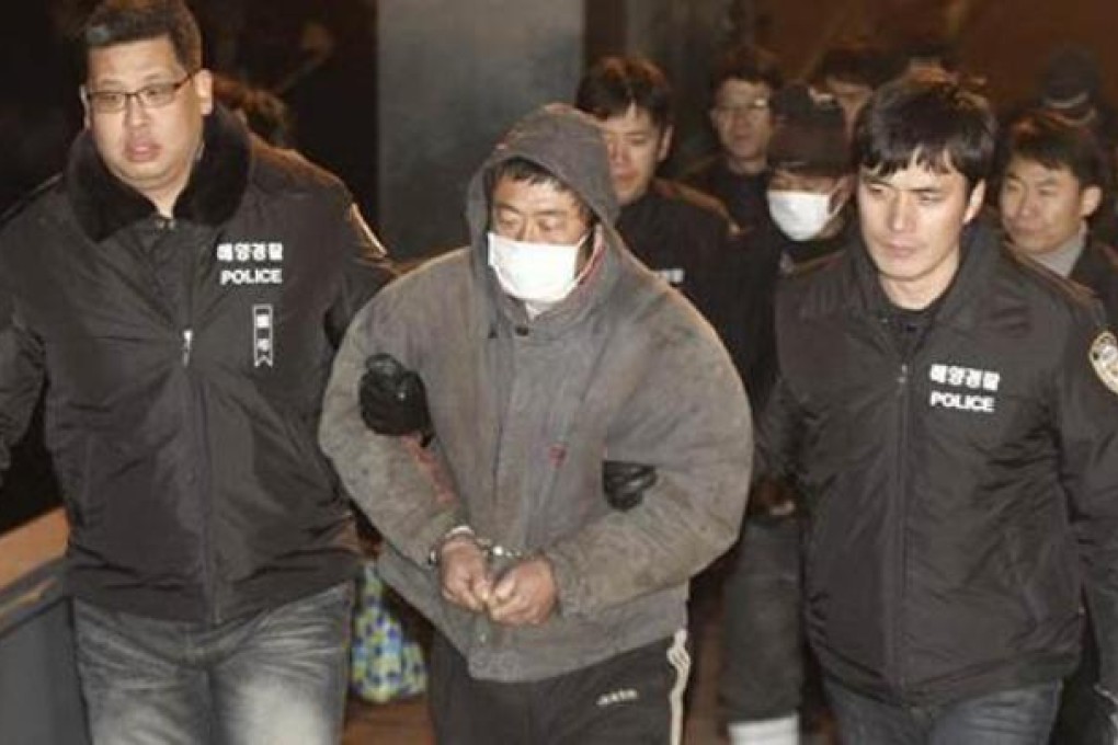 Cheng Dawei is escorted by South Korean police guards.