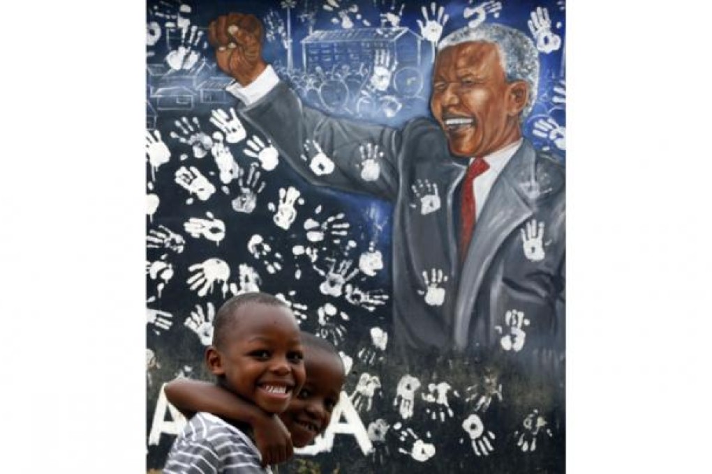 Two boys in a township near Johannesburg pose before a mural depicting Nelson Mandela, who remains widely revered. Photo: AP
