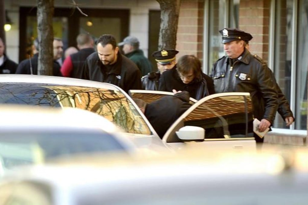 Ryan Lanza is escorted to a car by police after the shooting. Initially reported to have been the gunman, he is aiding their inquiries. Photo: AFP