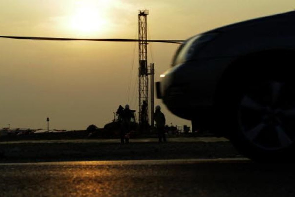 Oil workers stand at a facility site in the desert oil fields of Sakhir, Bahrain. Photo: AP
