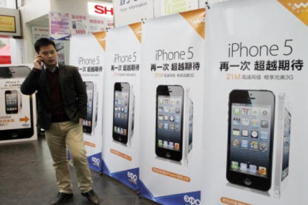 A customer stands in front of ad boards of Apple's iPhone 5 at a telecom retail store in Nanjing. Photo: Xinhua