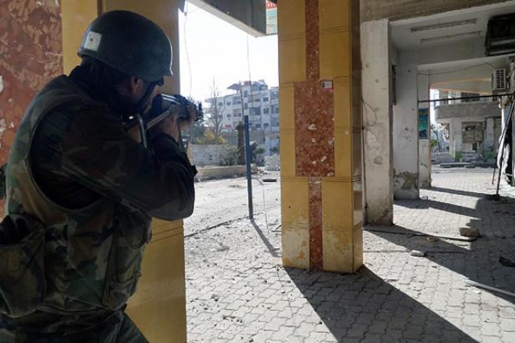 A Syrian government soldier aims his rifle at rebel fighters during clashes in the Damascus suburb of Daraya. Photo: AP